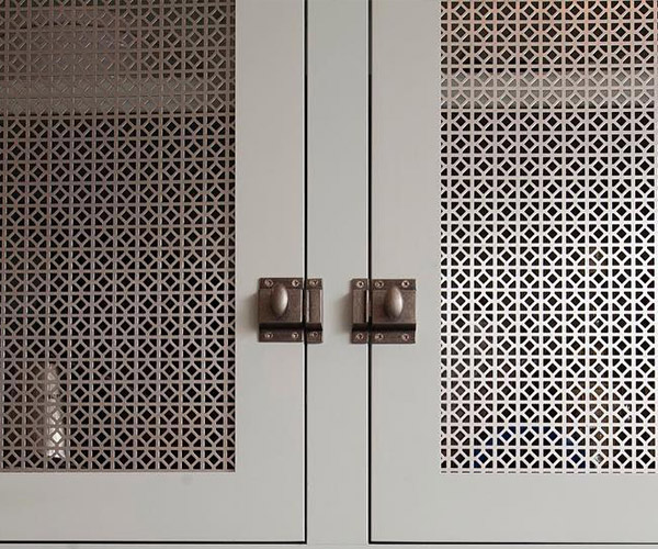 A picture of a white cabinet with Designer Perforated Metal inserts.