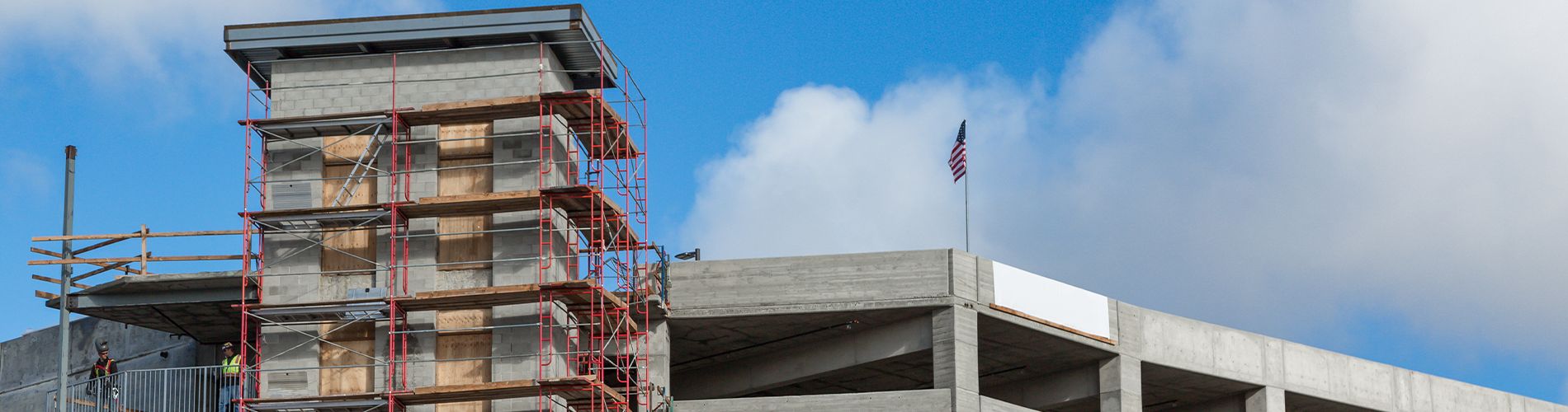 A picture of a parking garage under construction and an American Flag on top.