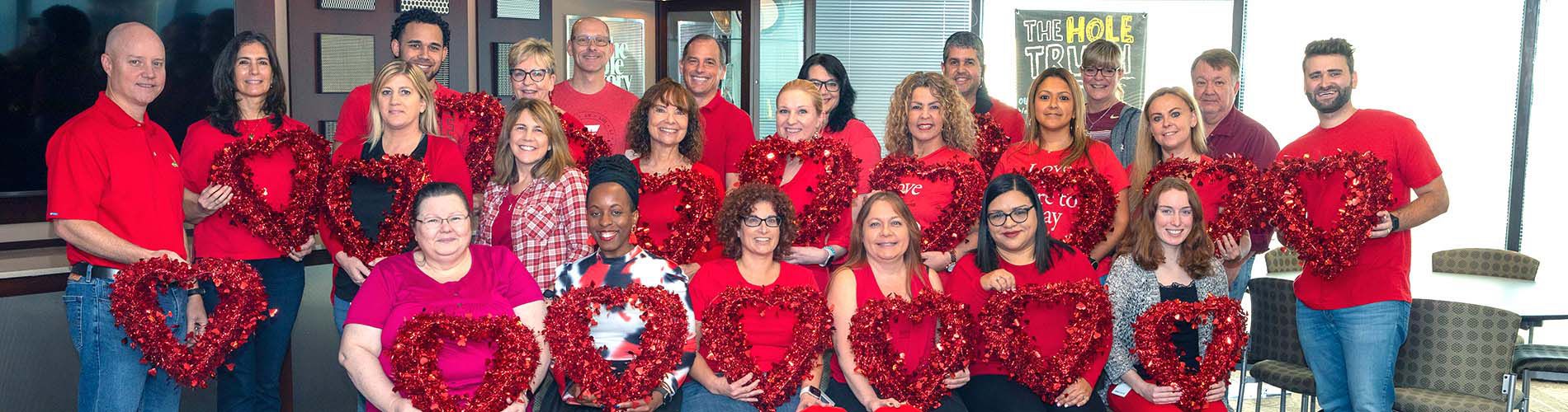 Employees smiling for a group picture on Wear Red Day for the American Heart Association.