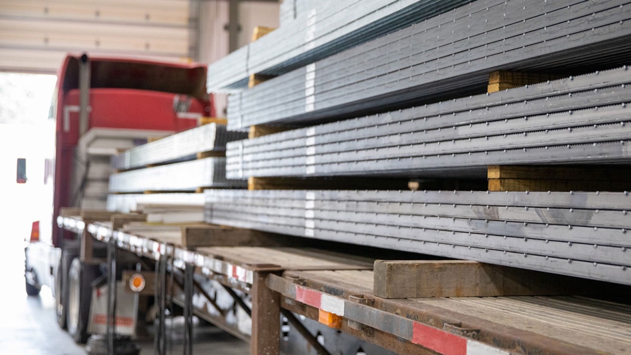 Image of a flatbed semi-truck that has several pieces of Bar Grating stacked on it.