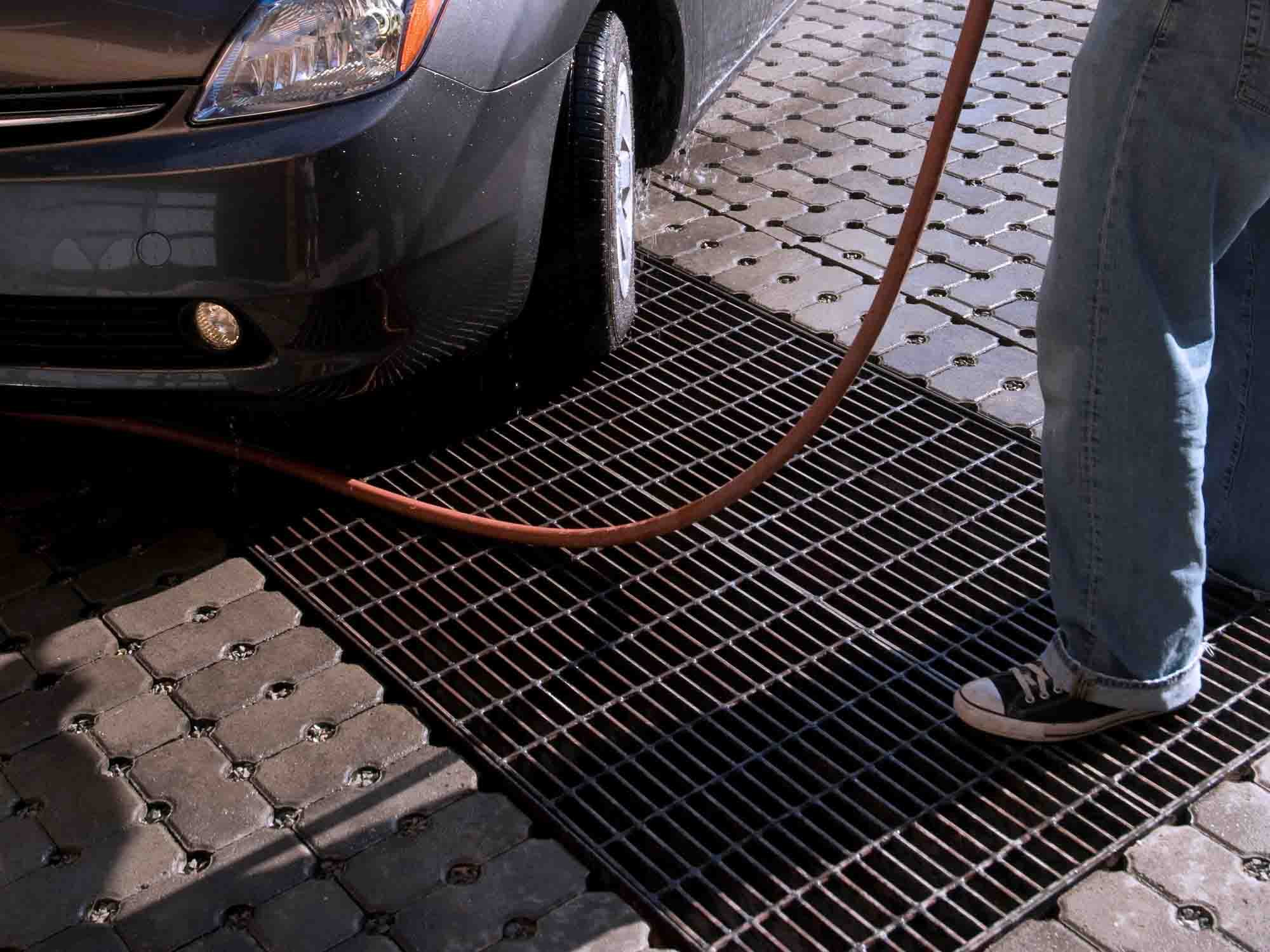 Picture of a person with a hose standing next to a car that is on a load-banded Bar Grating panel.