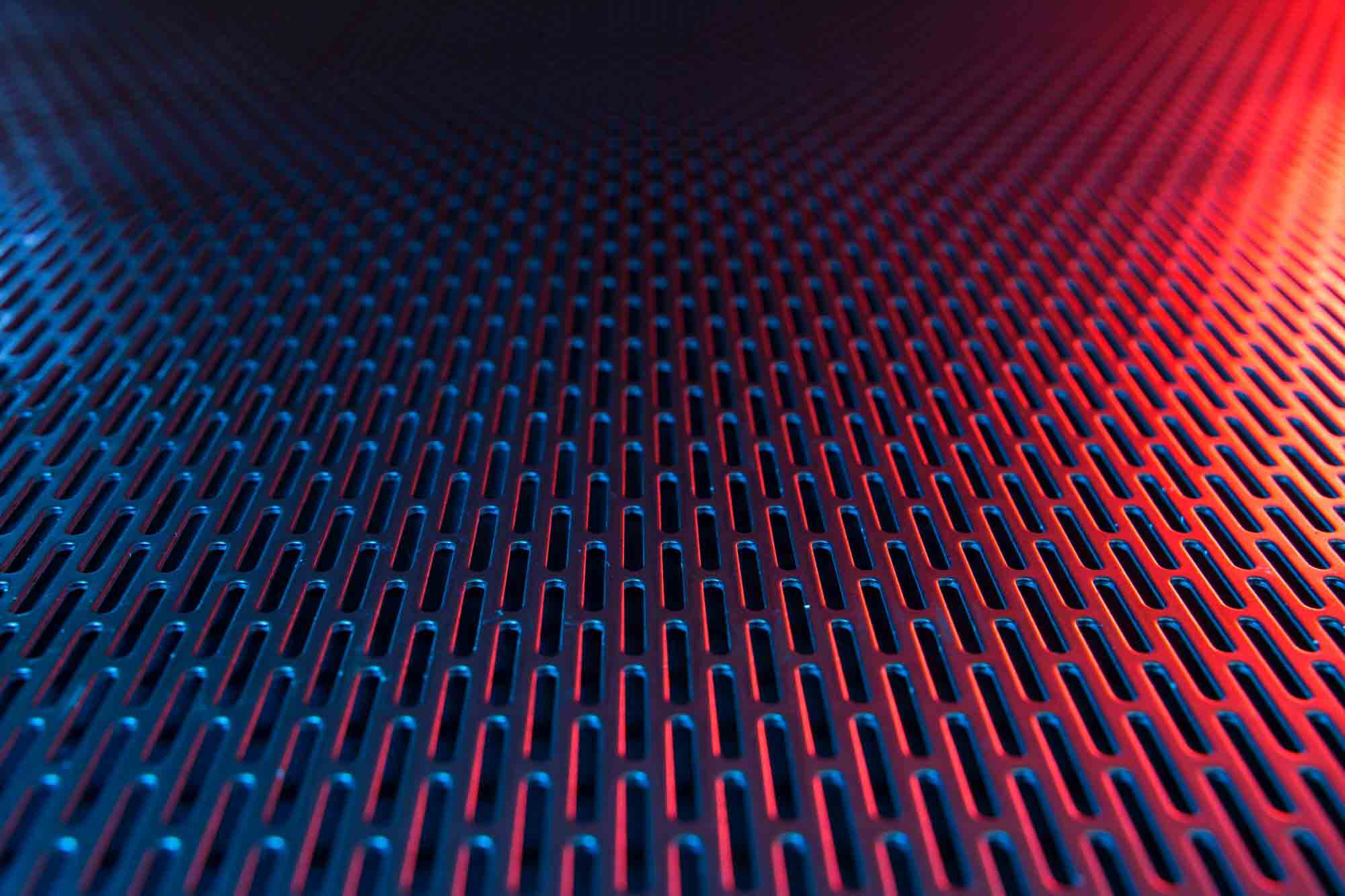 A close-up image of Stainless Steel Slotted Hole Perforated Metal with a red light shining on the right half.