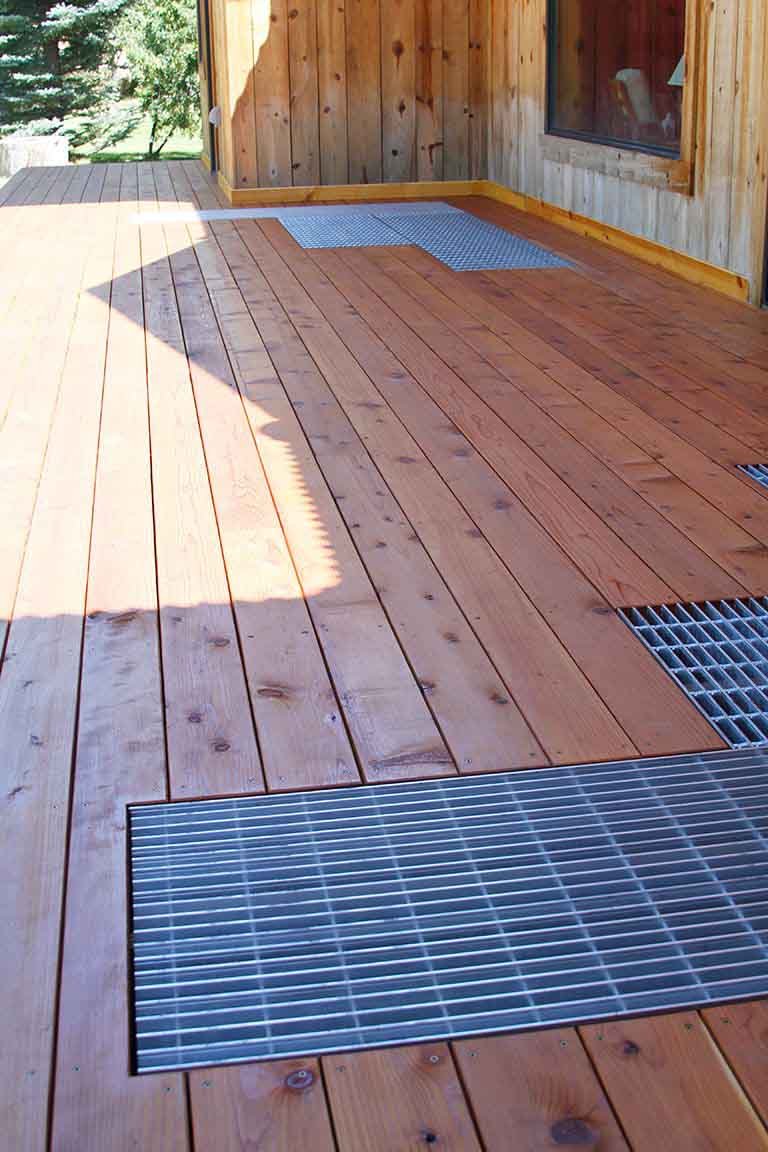 Grates that have been inserted into a backyard deck for drainage.