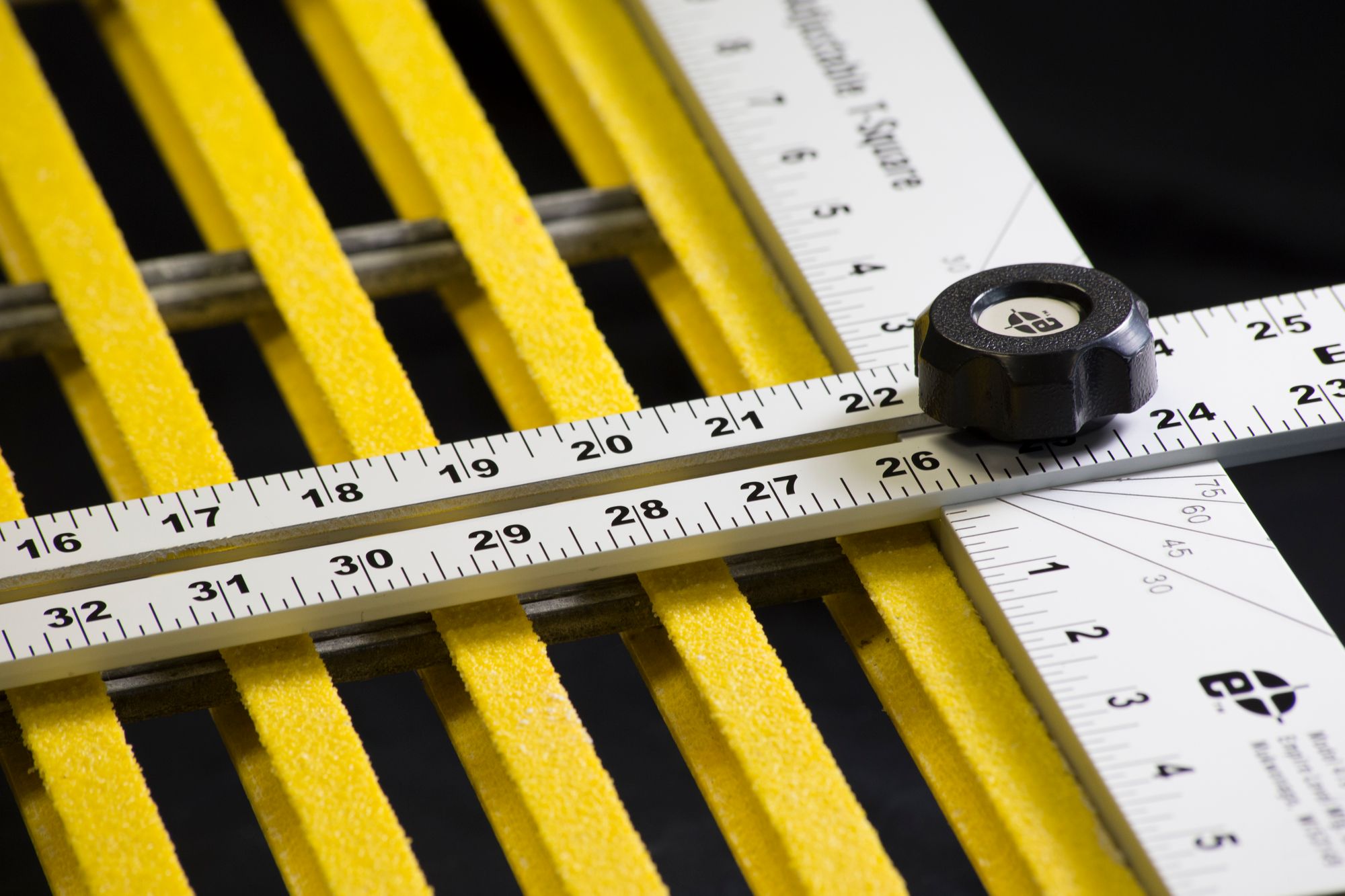 A closeup image of a measuring tool being used to prep for cutting Fiberglass Grating to size.