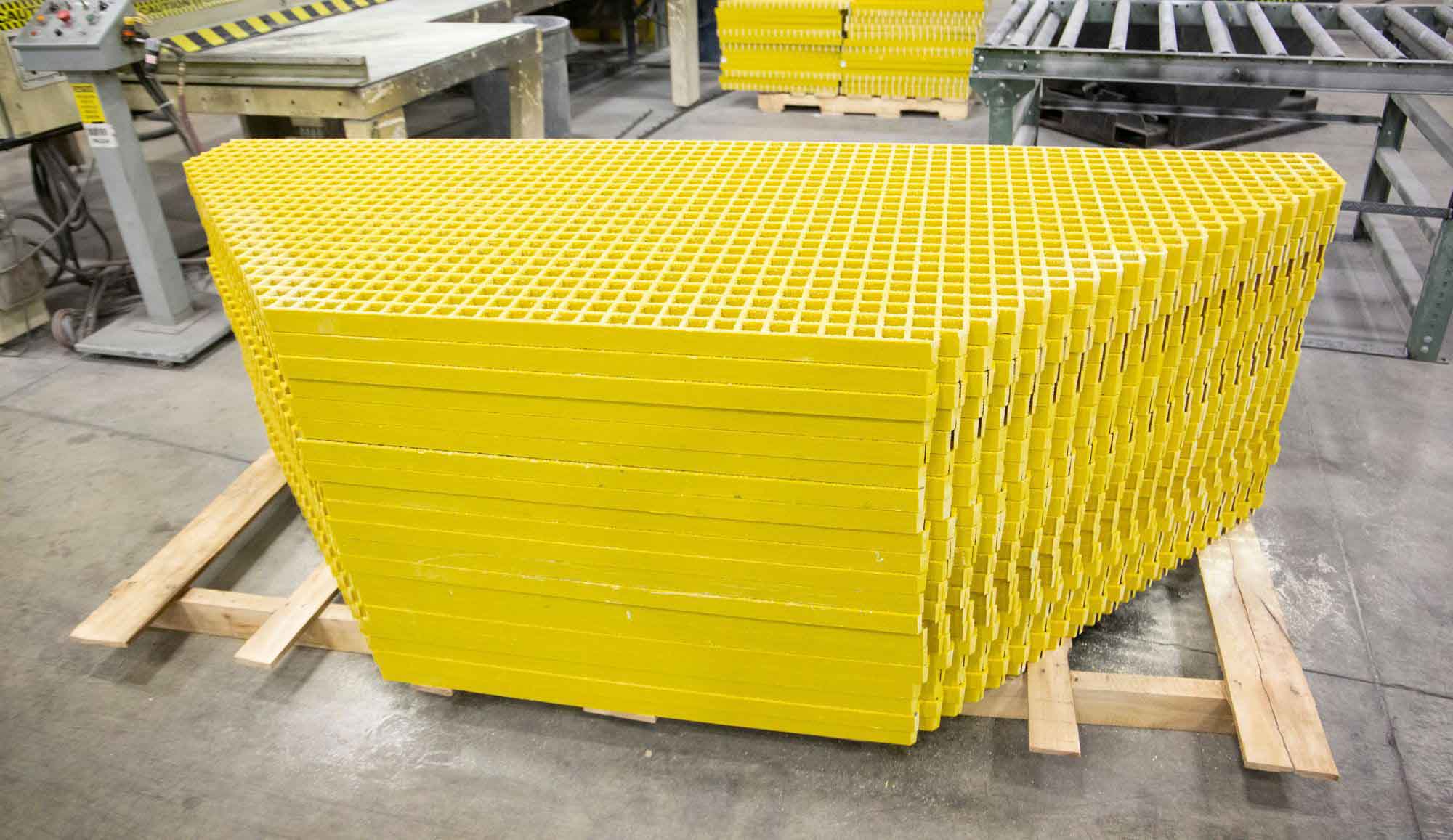 A large stack of yellow Fiberglass Grating that has been cut-to-size.