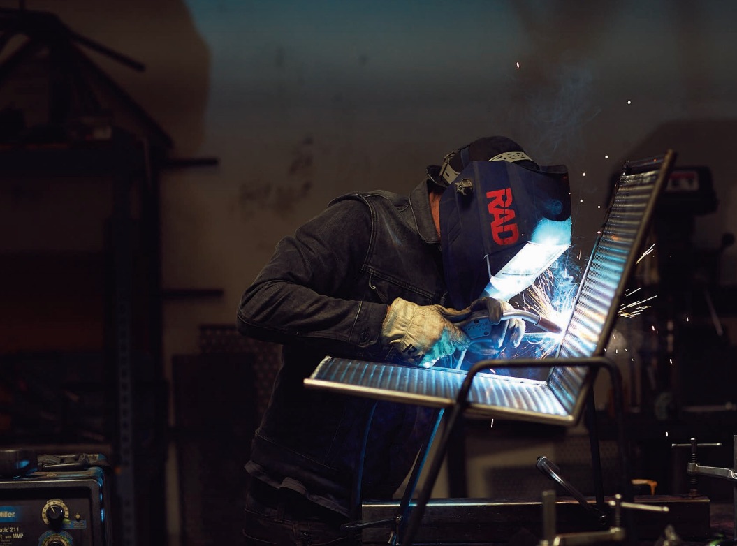 A fabricator from RAD Furniture that is welding parts of a Perforated Metal chair.
