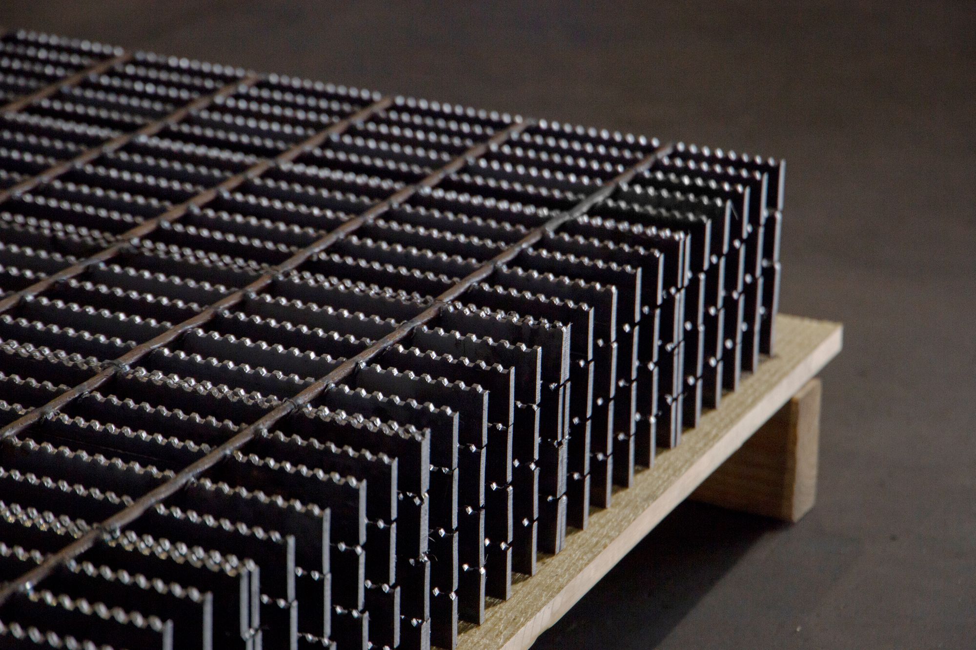 Four pieces of Serrated Bar Grating stacked on top of a wooden pallet.