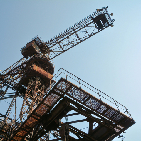 A crane in use at a construction site, shown from below.