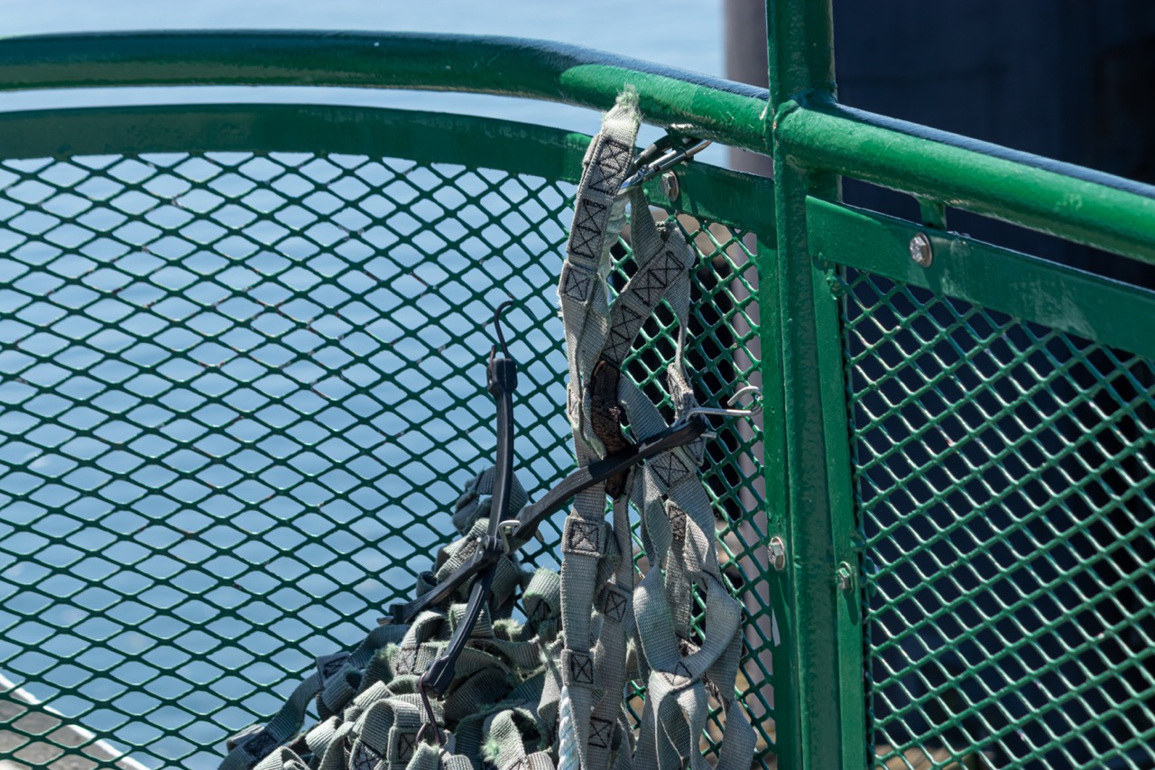 A gray netting made out of cloth hanging from a green railing and Expanded Metal panels.