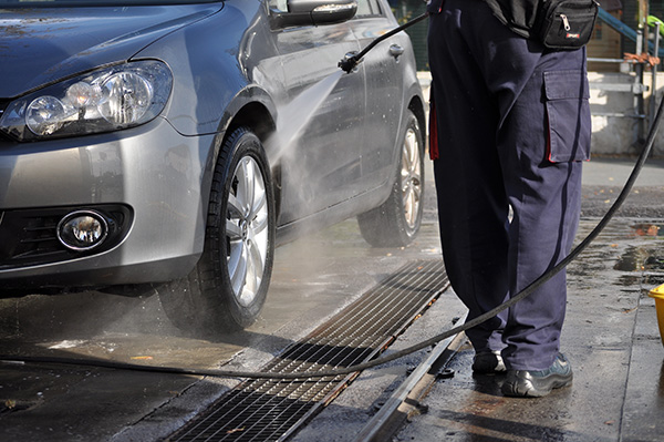 A picture of a worker next to a vehicle in a car wash line, highlighting the Bar Grating drain.