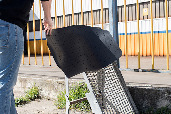 A picture of a person hanging a floor mat on a Wire Mesh drying rack at a car wash.