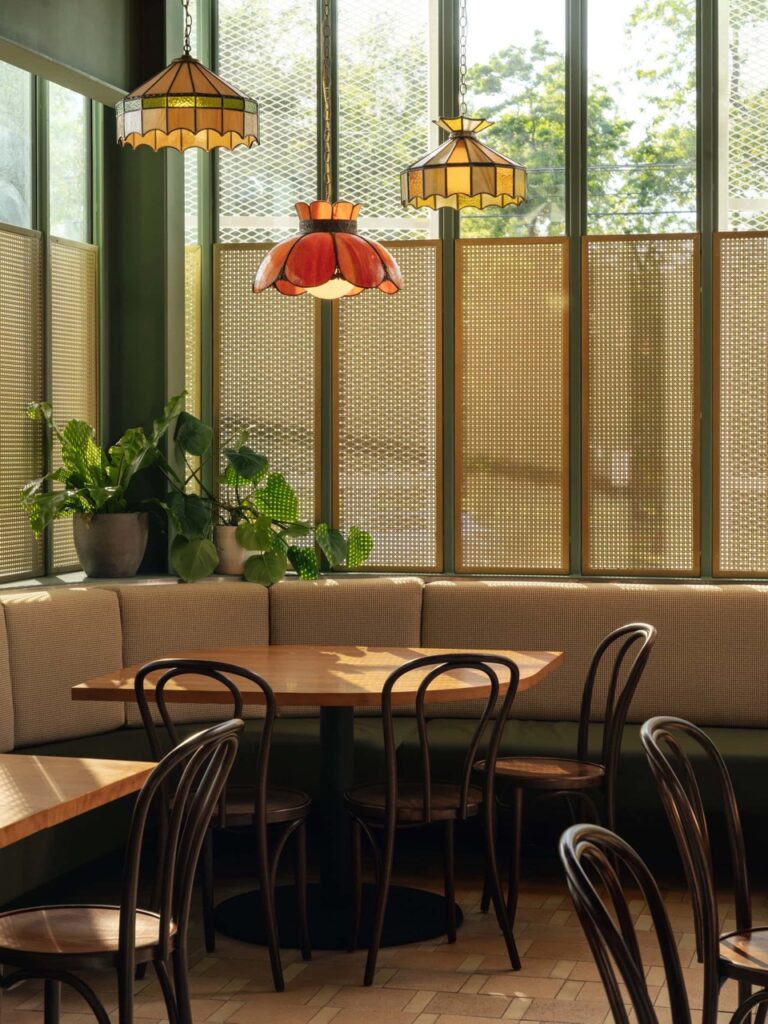 Interior dining area at Bambino Bar and Pizzeria featuring Designer Perforated OCTAGON CANE 2036 panels used as window screens behind booth seating, with pendant lighting and wood tables.