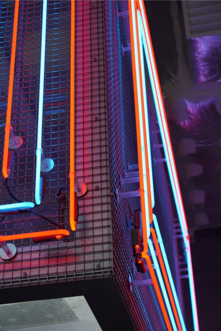 Close-up of Square Wire Mesh sheet that is Welded and Stainless Steel with red and blue neon lighting in a curved interior installation at POST Market Houston.