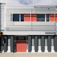 Building exterior with red panels and white framing, featuring Designer Mesh, AURA™ panels used as balcony and facade screening.
