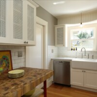 Kitchen with white cabinetry featuring Designer Perforated OCTAGON CANE 2236 inserts, adding a refined geometric pattern and ventilation to cabinet doors.