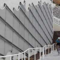Sloped walkway in a Cleveland pedestrian tunnel with Square Wire Mesh sheets with an Intercrimp Weave and framed with U-Edging on a concrete wall and a cyclist riding uphill.