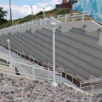 Wide view of a Cleveland pedestrian tunnel with sloped walkways, railings, and Square Wire Mesh sheets with an Intercrimp Weave and framed with U-Edging mounted along a concrete retaining wall.