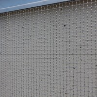 Close-up of Square Wire Mesh sheets with an Intercrimp Weave and framed with U-Edging in a metal frame mounted on a concrete wall in a Cleveland pedestrian tunnel.