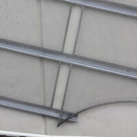 Angled close-up of Square Wire Mesh sheets with an Intercrimp Weave and framed with U-Edging mounted on a concrete wall in a Cleveland pedestrian tunnel.