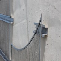 Close-up of curved Square Wire Mesh sheets with an Intercrimp Weave and framed with U-Edging mounted to a concrete wall in a Cleveland pedestrian tunnel.