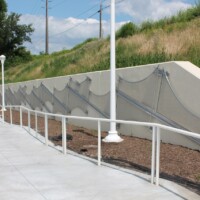 Wide view of Square Wire Mesh sheets with an Intercrimp Weave and framed with U-Edging installed along a sloped concrete wall beside a walkway in a Cleveland pedestrian tunnel.