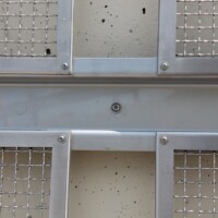 Close-up of Square Wire Mesh sheets with an Intercrimp Weave and framed with U-Edging, mounted on a concrete wall in a Cleveland pedestrian tunnel.
