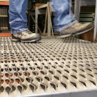 Someone standing on a platform in a warehouse made out of 5-Diamond GRIP STRUT® Plank Grating.