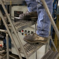 Someone walking on 3-Diamond GRIP STRUT® Plank Grating stair treads that make up an industrial ladder.