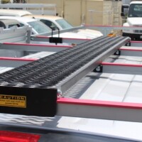 Powder-coated black 5-Diamond GRIP STRUT® Plank Grating mounted on van roof rack for traction and load support.