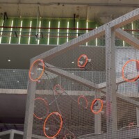 Square Wire Mesh sheet that is Welded and Stainless Steel with circular neon lighting elements in a multi-level interior installation at POST Market Houston.