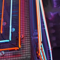 Close-up of Square Wire Mesh sheet that is Welded and Stainless Steel with red and blue neon lighting in a curved interior installation at POST Market Houston.