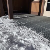 Snow-covered entryway with 10-Diamond GRIP STRUT® Plank Grating flooring providing traction outside building entrance.