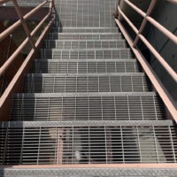 Press-Locked Bar Grating Stair Treads on an industrial staircase with metal handrails and grated landings.