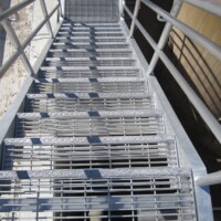 Aluminum Swage-Locked Bar Grating Stair Treads installed on an industrial metal staircase with handrails.