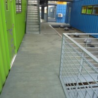 Exterior area at The Box Office building with TRACTION TREAD™ Plank Grating flooring and stairs between recycled shipping container units.
