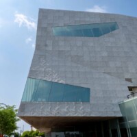 Angled exterior view of the Walker Art Center in Minneapolis, MN, showcasing Designer Expanded Metal, Flattened LANCET™ 31651-F facade with geometric windows and textured panels above a pedestrian walkway and lawn.