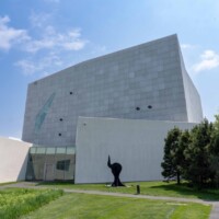 Wide exterior view of the Walker Art Center in Minneapolis, MN, featuring Designer Expanded Metal, Flattened LANCET™ 31651-F facade with angular forms, surrounding lawn, trees, and sculpture in the foreground.