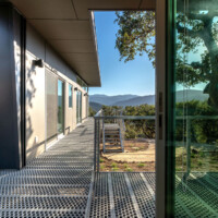 Covered exterior corridor showcasing 6-Hole PERF-O GRIP® Plank Grating flooring with mountain views beyond.