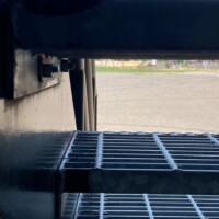 Close-up side view of Standard-Duty Welded Bar Grating Stair Treads on a metal staircase, showing open grid construction and structural support framing.