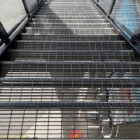 Exterior Staircase with Smooth Standard-Duty Welded Bar Grating Stair Treads and metal handrails in a commercial or industrial facility.